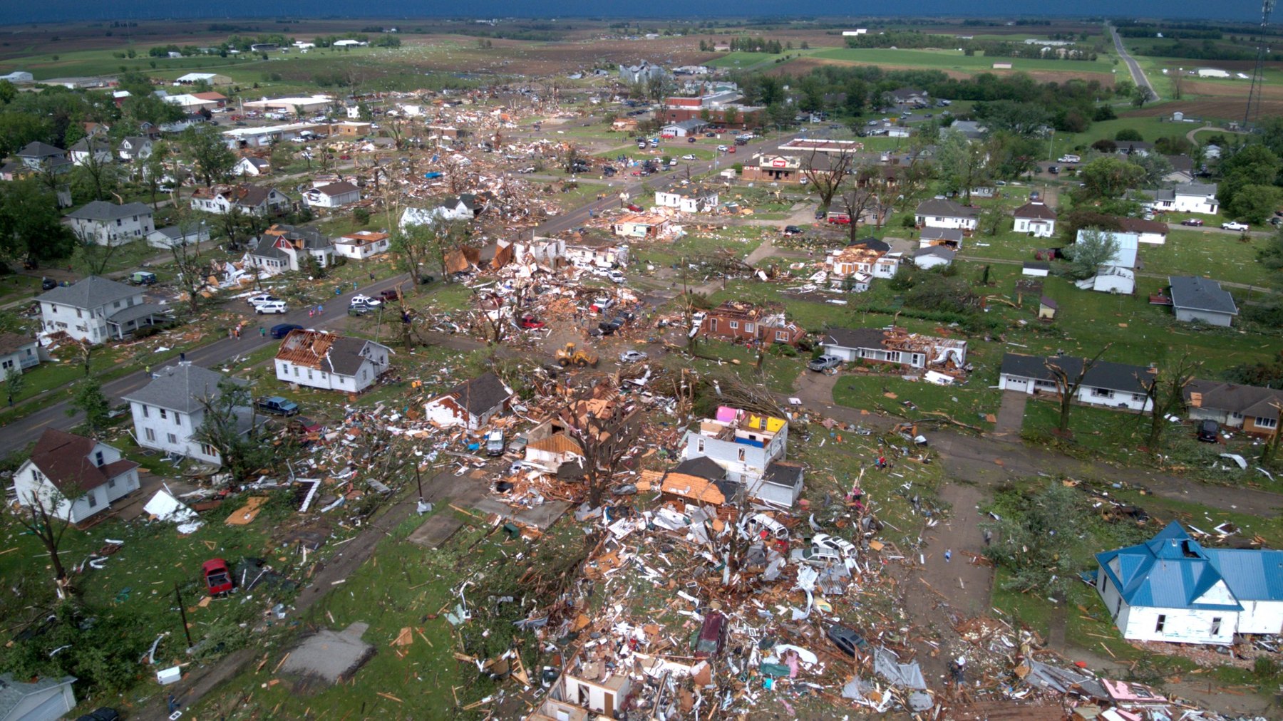 Wide aerial drone storm damage photo showing a damaged town and surrounding farmland after severe weather